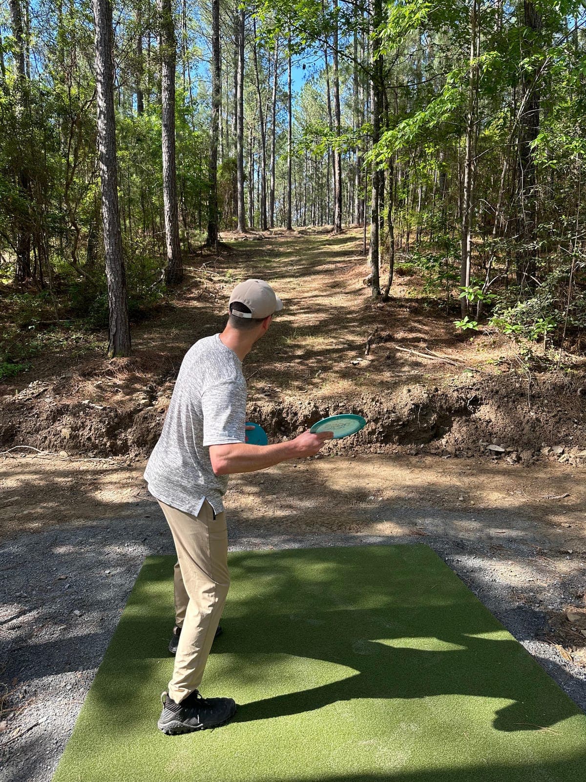 Justin throwing a disc from a tee pad in the woods