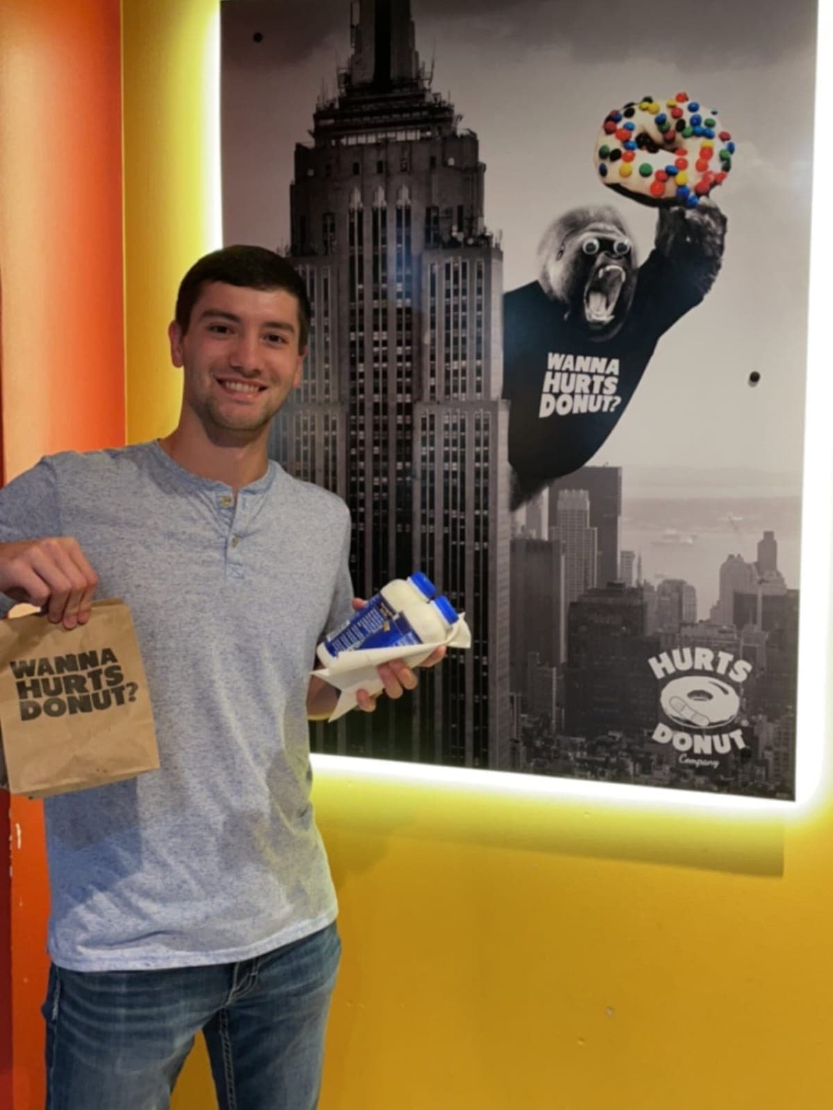 Justin holding a Hurts Donut bag and a box of donuts