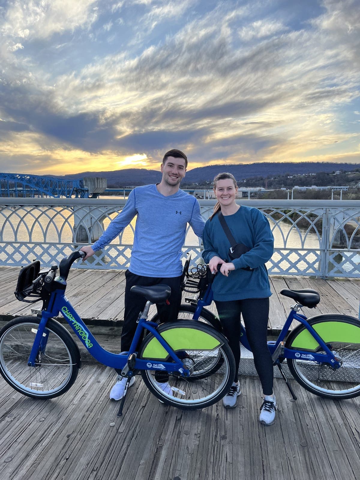 Justin and his wife with bikes on a bridge at sunset