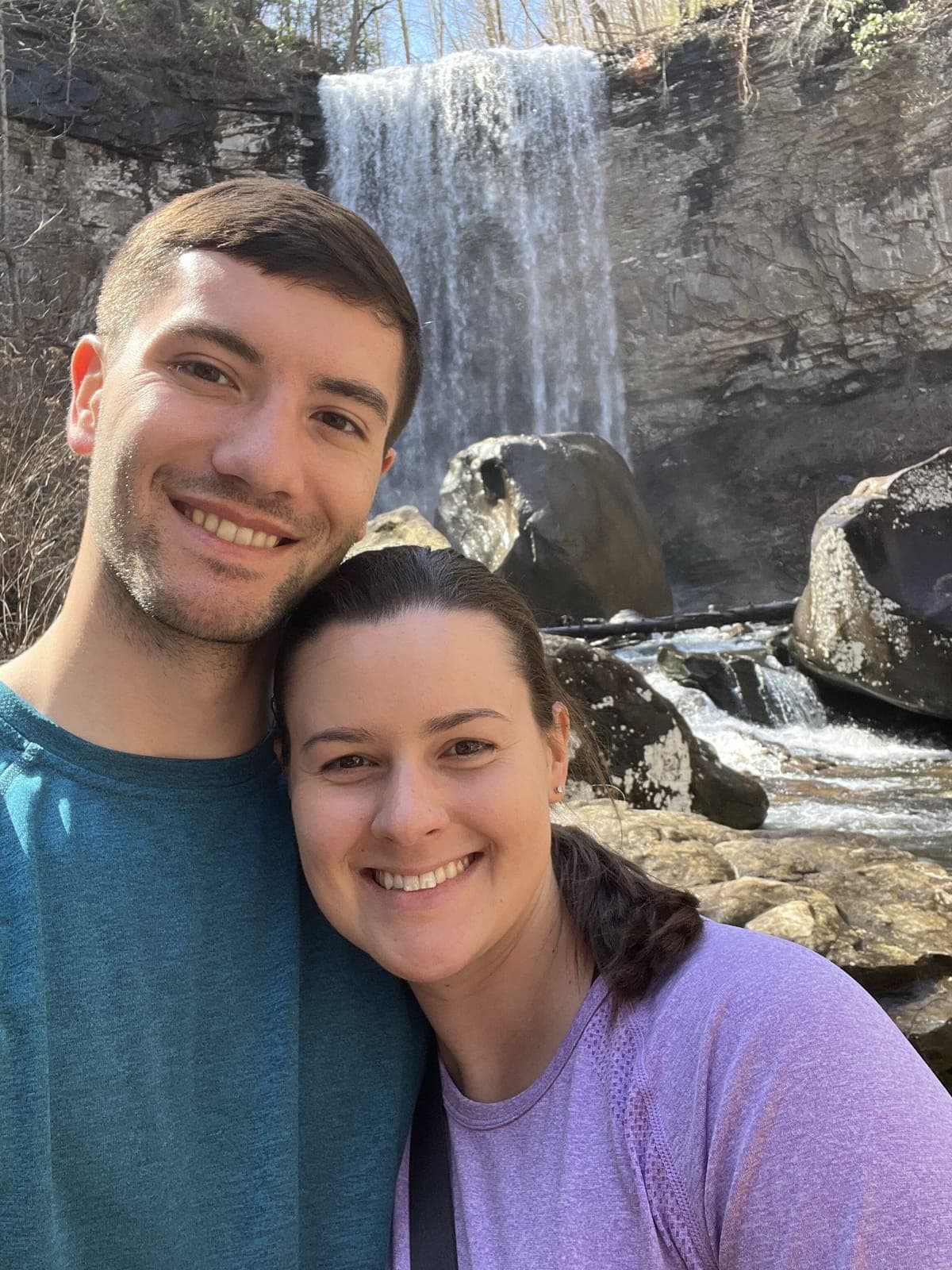 Justin and his wife smiling in front of a waterfall
